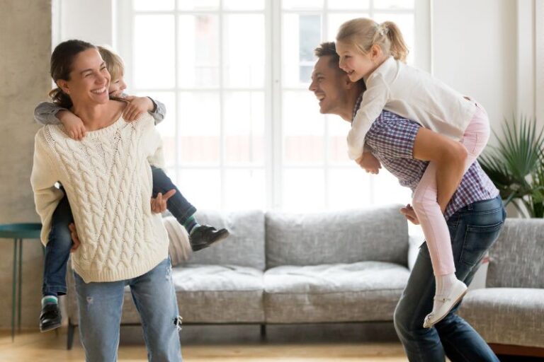 Mensen voorkomen spit en dansen in de woonkamer met hun kinderen op hun rug terwijl ze blij kijken.