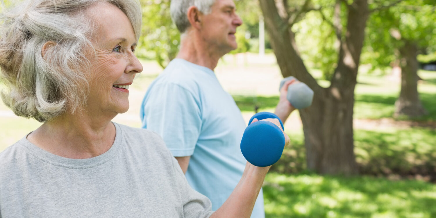 Twee oude mensen sporten samen buiten en moeten actief blijven met parkinson.