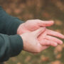 Man zit aan zijn hand omdat hij last heeft van tintelingen in zijn hand en vingers.