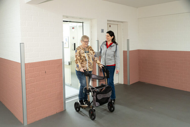 spier- en gewrichtspijn door kou Fysiotherapeut helpt oudere vrouw met bewegen tegen spier- en gewrichtspijn door kou.